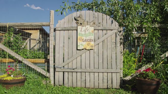 举着写着“花园生活更美好”的牌子走近花园大门