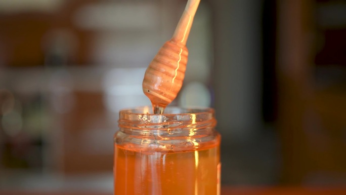 蜂蜜滴，从特殊的蜂蜜勺倒在玻璃碗里