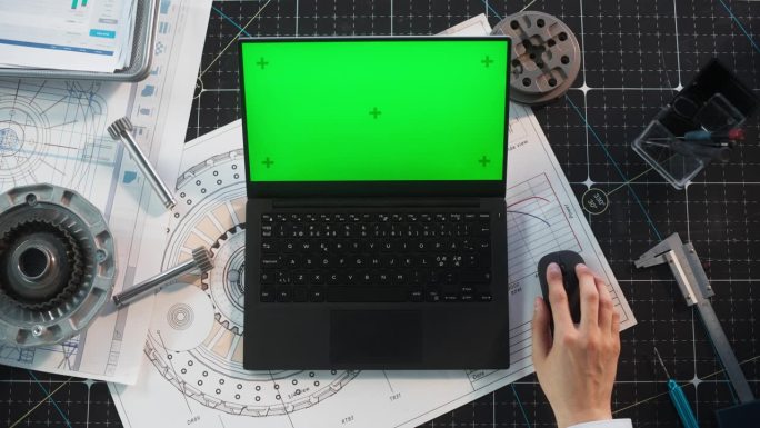 匿名工业专家使用笔记本电脑模拟绿屏Chromakey显示与占位符。一个人坐在桌子后面，用无线鼠标上网