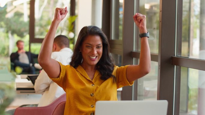 兴奋成熟的女商人拿着笔记本电脑在办公室庆祝好消息