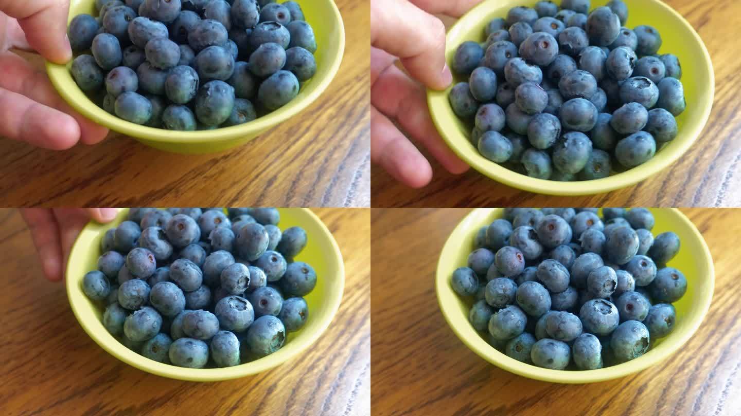 蓝莓在碗里。那只手把一盘浆果放在桌子上。新鲜的蓝莓。吃健康食品的镜头。获得维生素。4 k的视频。