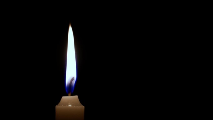 镜头从黑色背景下明亮燃烧的蜡烛上拉开。