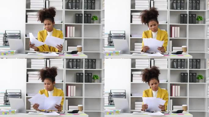 严肃的非裔美国女商人在办公室里忙于文书工作。阅读财务账单和发票的压力大的女人。