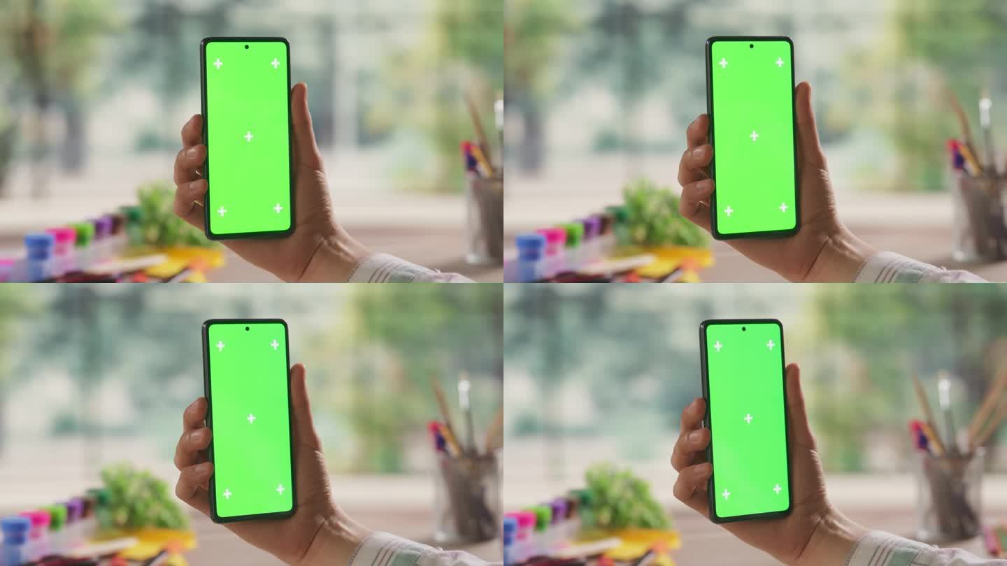 有创意的学者在智能手机上用模拟绿屏Chromakey显示屏检查社交网络帖子。视频模板与艺术设计广告和