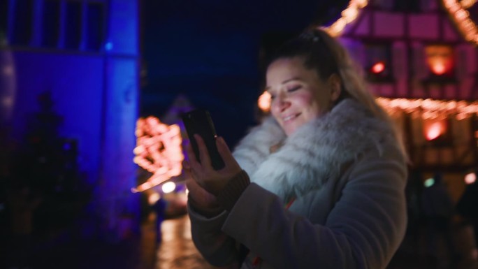 一名妇女在科尔马镇的圣诞市场使用她的智能手机