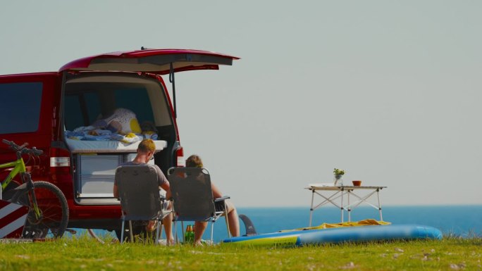 一对夫妇在海边露营车外的椅子上休息。有风景的午餐