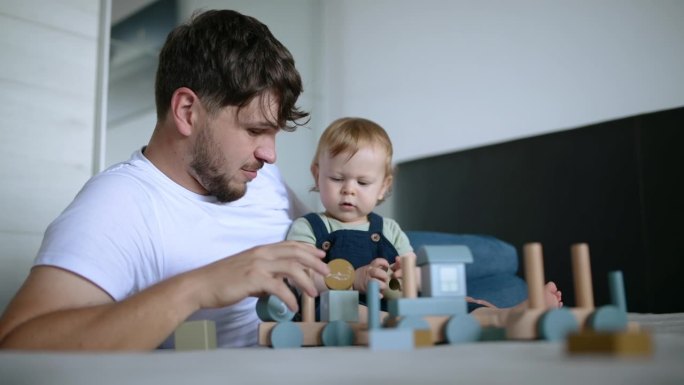 父亲和他的儿子一起用玩具积木制作木制火车。