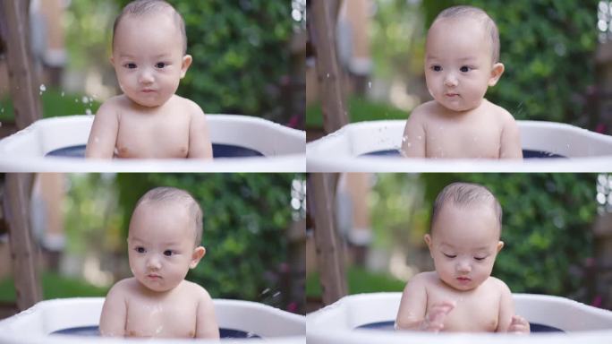 小男孩玩得很开心，把水溅到婴儿浴盆上。