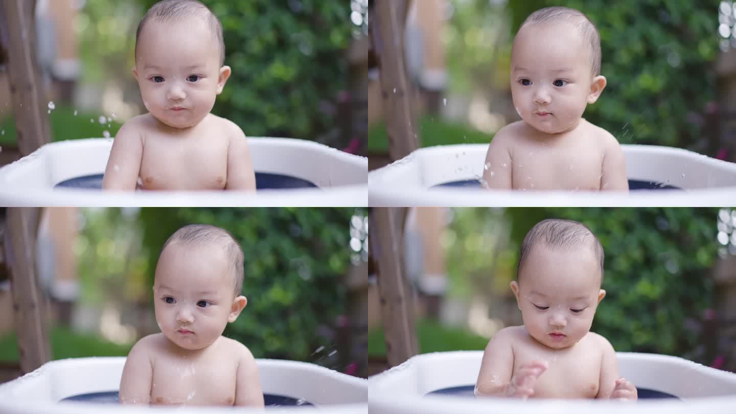 小男孩玩得很开心，把水溅到婴儿浴盆上。