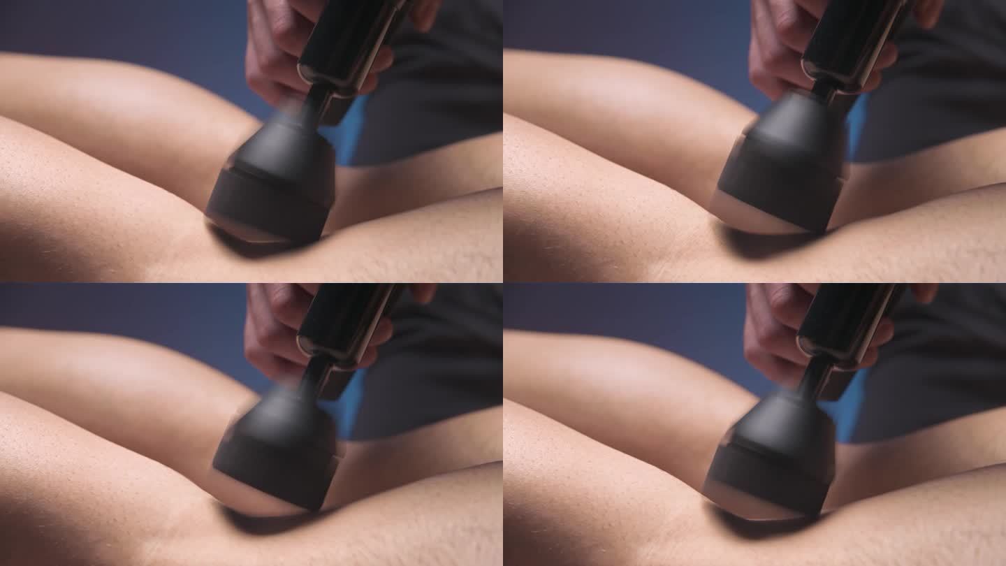 专业男按摩师在黑暗的水疗室里刺激男病人的腿部肌肉进行按摩的特写。冲击机械对过度劳损肌肉的影响