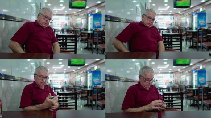 坐在巴西自助餐厅里的老人戴上老花镜，从口袋里掏出手机。老年人在餐厅内使用现代科技智能手机