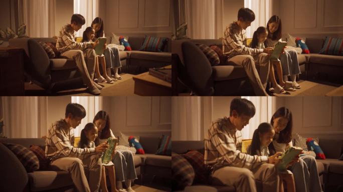 幸福的韩国家庭在家里共度时光:可爱的孩子和她的父母一起玩数码平板电脑。小女孩在慈爱的父母的照顾下享受