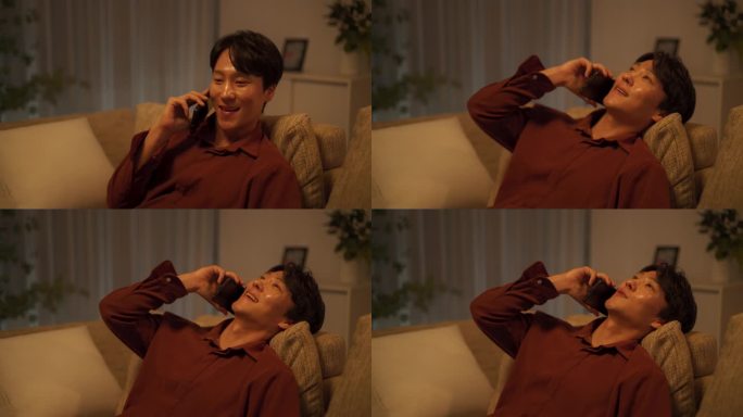 英俊的韩国年轻人晚上在舒适的沙发上放松，一边愉快地打电话，一边和朋友随意聊天，讲有趣的故事
