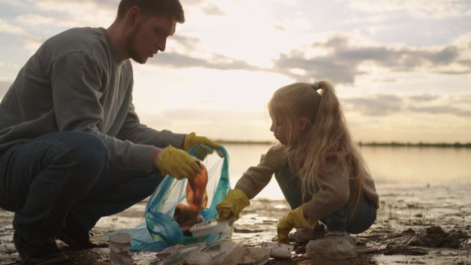 小女孩帮助爸爸清理湖岸的塑料垃圾，生态概念