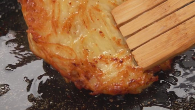 木铲在锅里翻动用沸油煎过的土豆饼