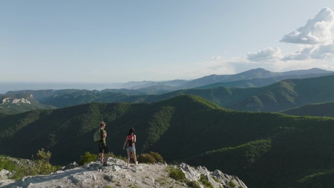 登山夫妇登上山顶欣赏海岸山景