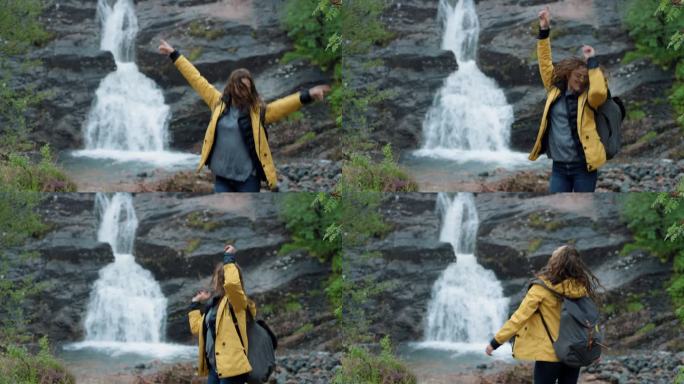 在雨中跳舞的女人在户外瀑布前傻傻的自由舞蹈，疯狂的舞蹈女孩享受大自然，庆祝假期旅行冒险