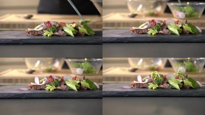 辣味泰式牛肉切片沙拉是用多种食材制作的，包括绿色蔬菜、红萝卜和粉红色的花。在长方形石板上，排列整齐。