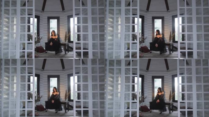 黑衣女歌手坐在沙发上，在录音棚里创作音乐录影带