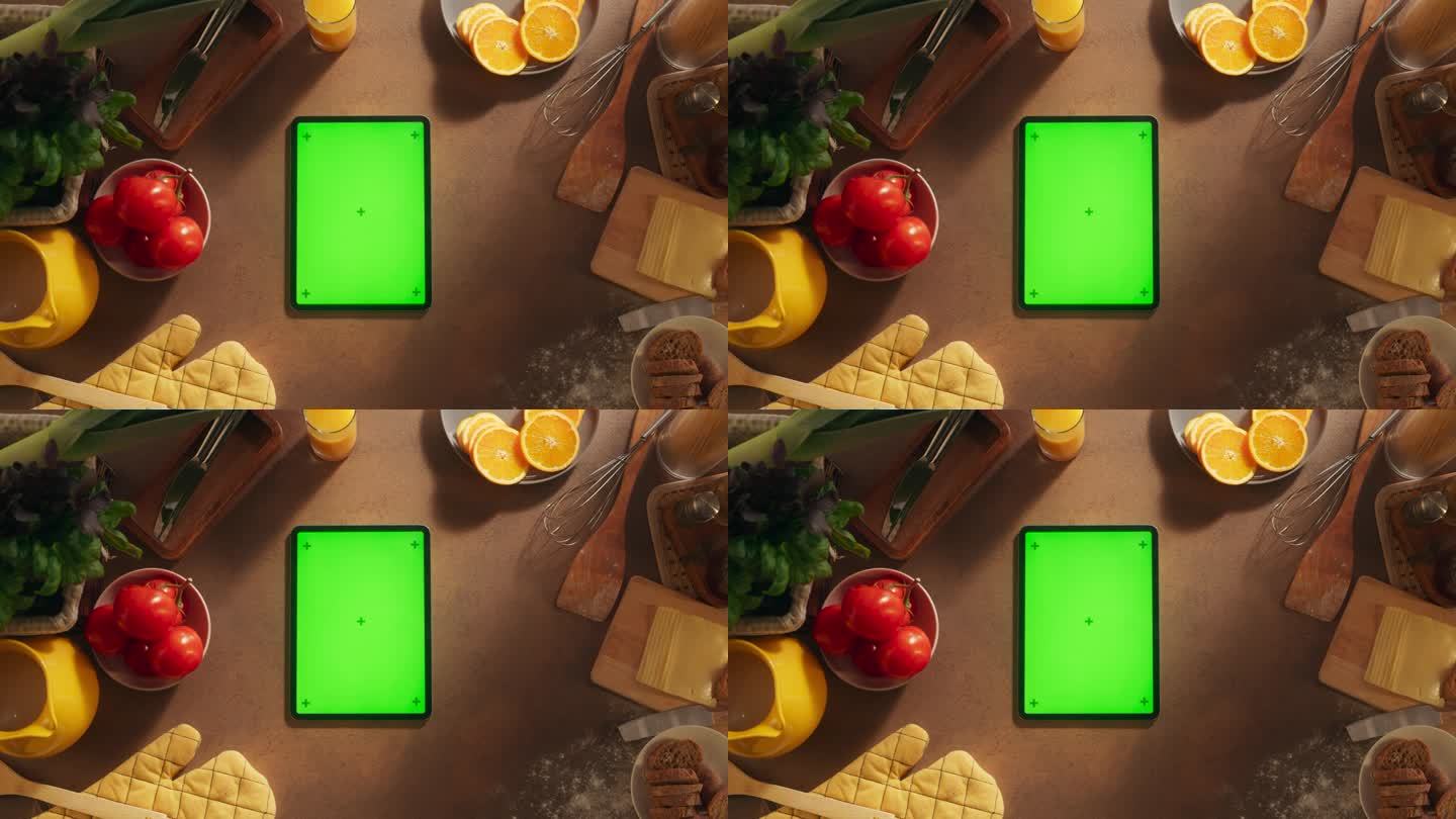 一个平板电脑与模拟绿色屏幕显示的自上而下的视图。一个设备垂直躺在厨房桌子上的静态镜头。在线烹饪和食物