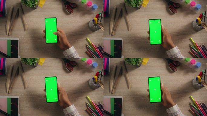 设计师在智能手机上滚动应用程序与绿屏Chromakey模拟显示在一个创造性的工作场所。视频模板与隔离