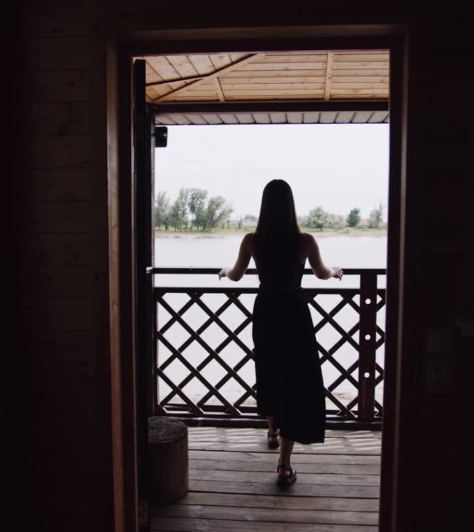一个女孩在河边阳台上的剪影。垂直视频