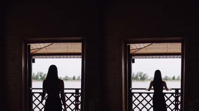 一个女孩在河边阳台上的剪影。垂直视频