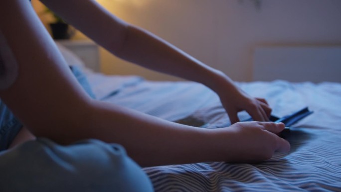 糖尿病女孩坐在家里的床上用手机应用检查胰岛素水平的特写