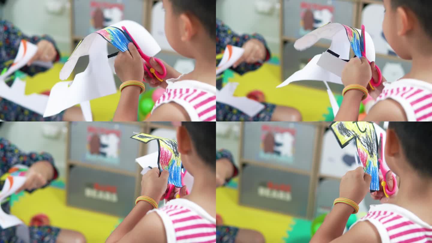小男孩练习剪刀彩色剪纸卡通形象。