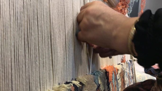 一位妇女编织传统手工地毯的双手