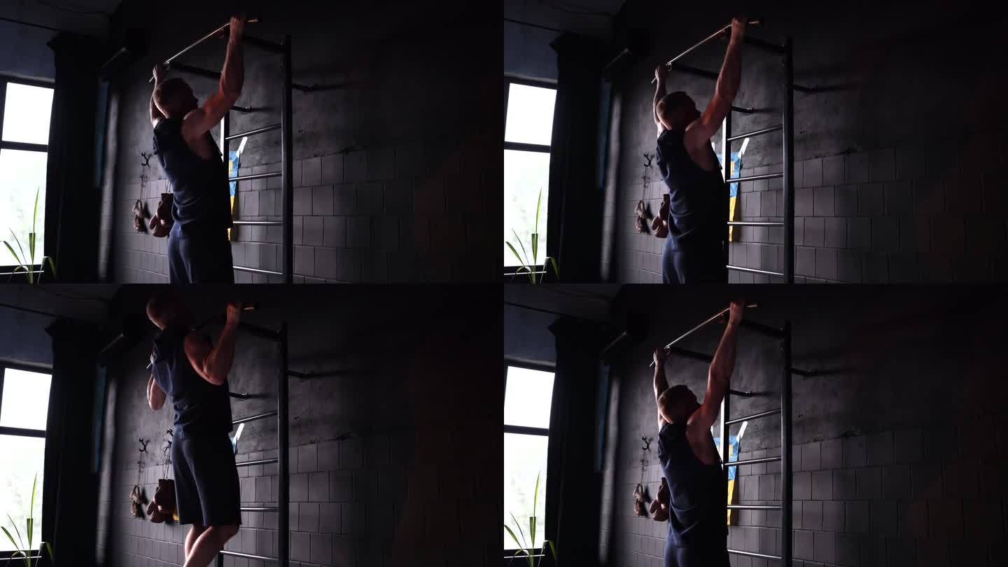 男运动员在健身房锻炼时在横杆上向上拉。