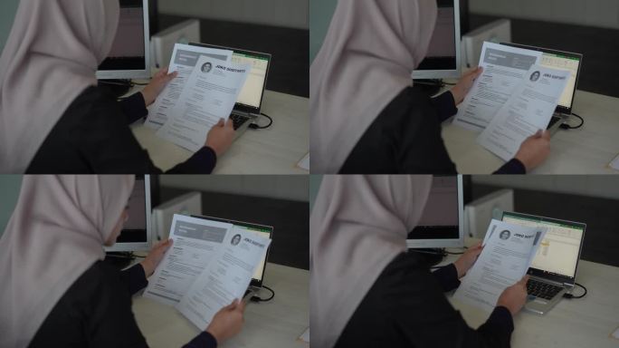 商业穆斯林妇女阅读纸上的简历来雇用合适的人员