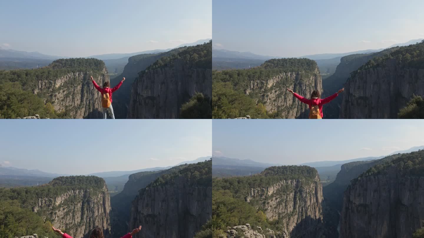 泰兹峡谷的鸟瞰图。女孩站在山上欣赏美丽的景色。在峡谷背景下的悬崖上，穿着红色夹克的女游客徒步旅行。神