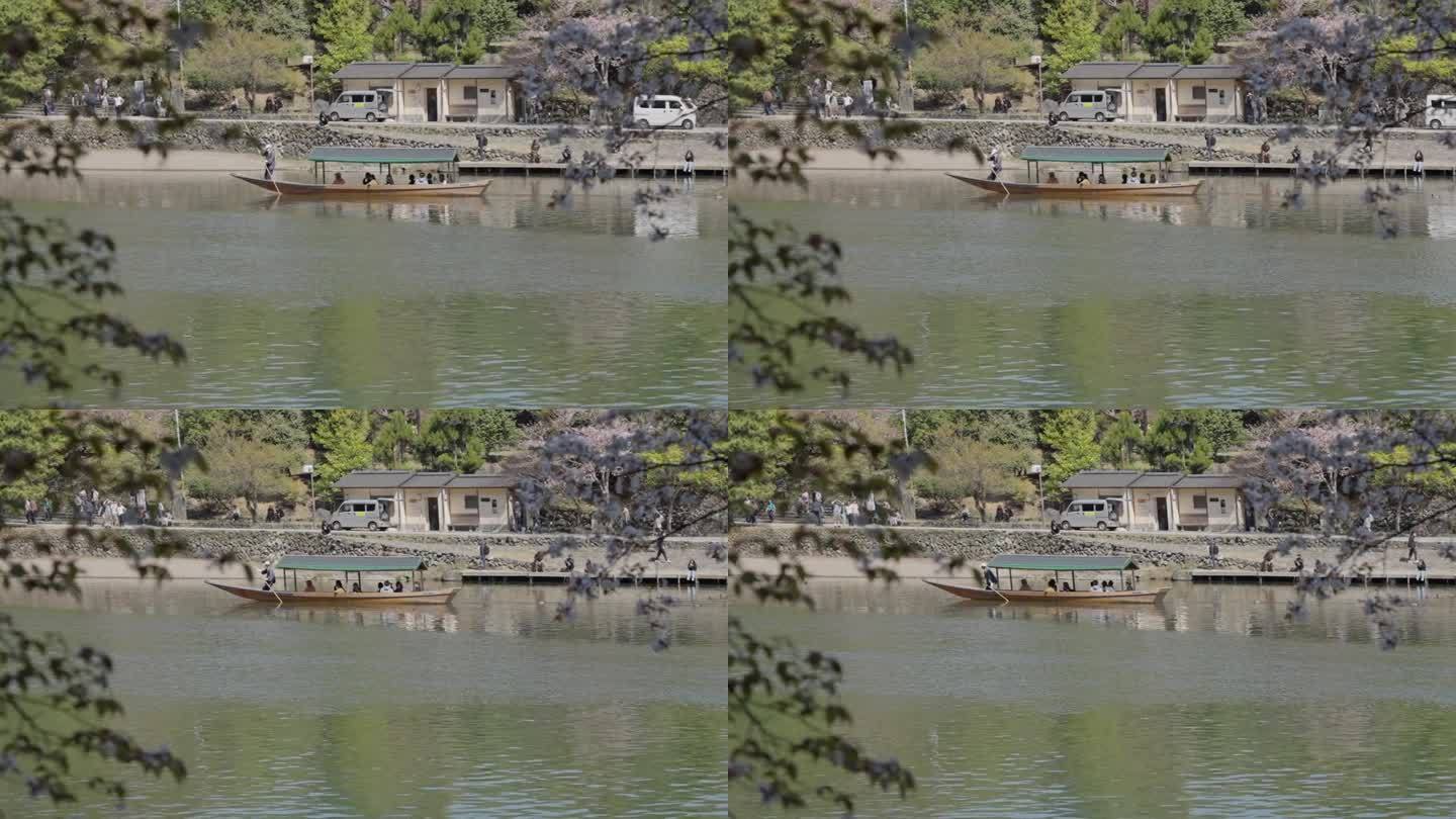 游客们在岚山河上乘船欣赏樱花