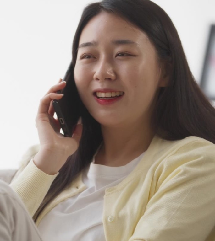 垂直屏幕:美丽微笑的韩国女人正在和女朋友打电话，谈论最新的时尚潮流和最喜欢的电视人物