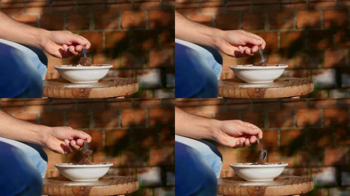 后院午餐:在户外吃豆子的人。一碗在阳光下煮熟的豆子。用勺子吃feijoada(煮豆)的人。太阳下的一