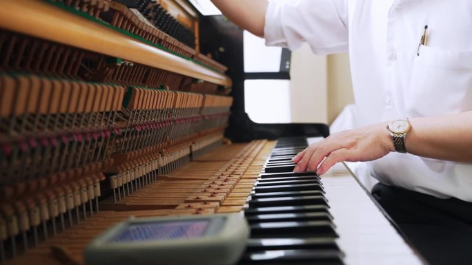 专业维修人员和音乐调音师的手在清理打开的钢琴。