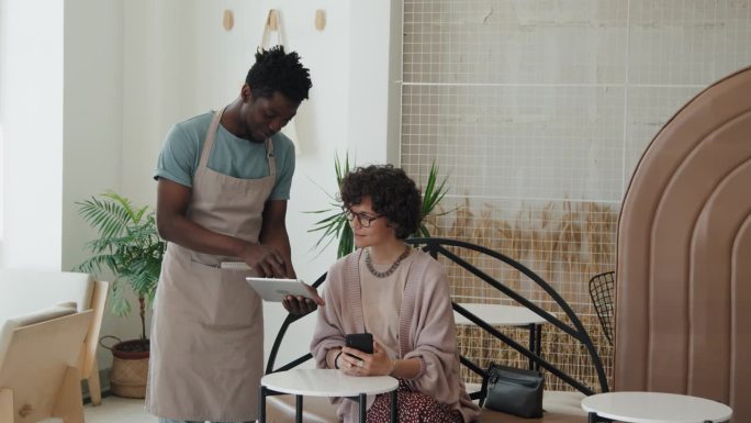 非裔美国服务员在平板电脑上展示白人女性菜单