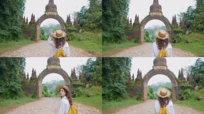 戴草帽的妇女走在通往泰国丛林中一座古庙的大门附近