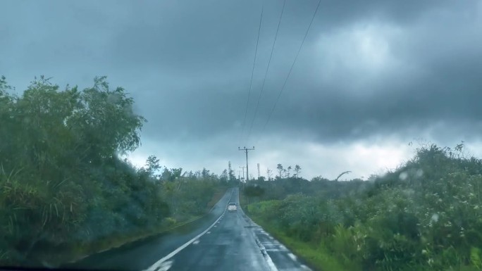 大雨下，行驶在毛里求斯岛内陆公路上的右手驾车。司机在车内观看4K视频。