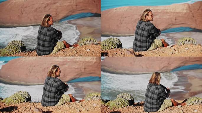 男游客坐在悬崖上欣赏大自然的后视图