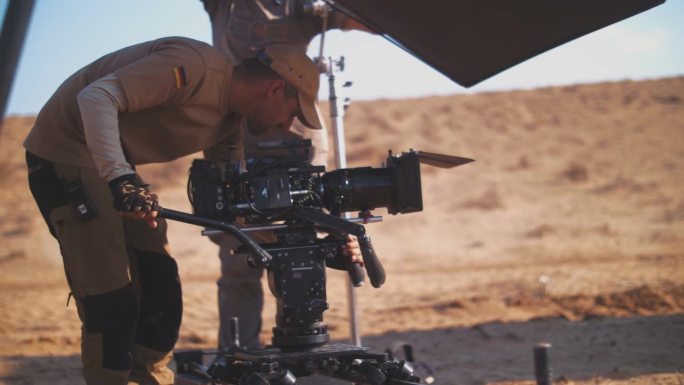 在大草原上拍摄。操作员沿着滑块移动摄像机。摄制组。在沙漠里拍电影
