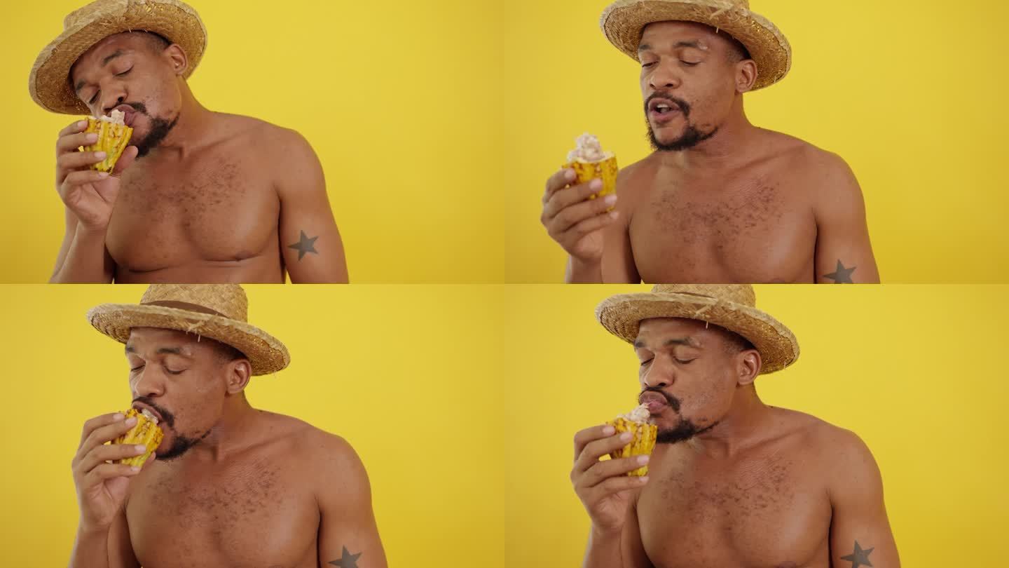 快乐的中年非洲裔美国人有胡子和裸体吃新鲜成熟的黄色可可豆荚打开半切可可果在黄色背景。裸体男人拿着新鲜