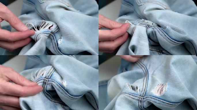 手在牛仔裤上摸索洞的特写。裁缝检查两腿之间擦出的洞。