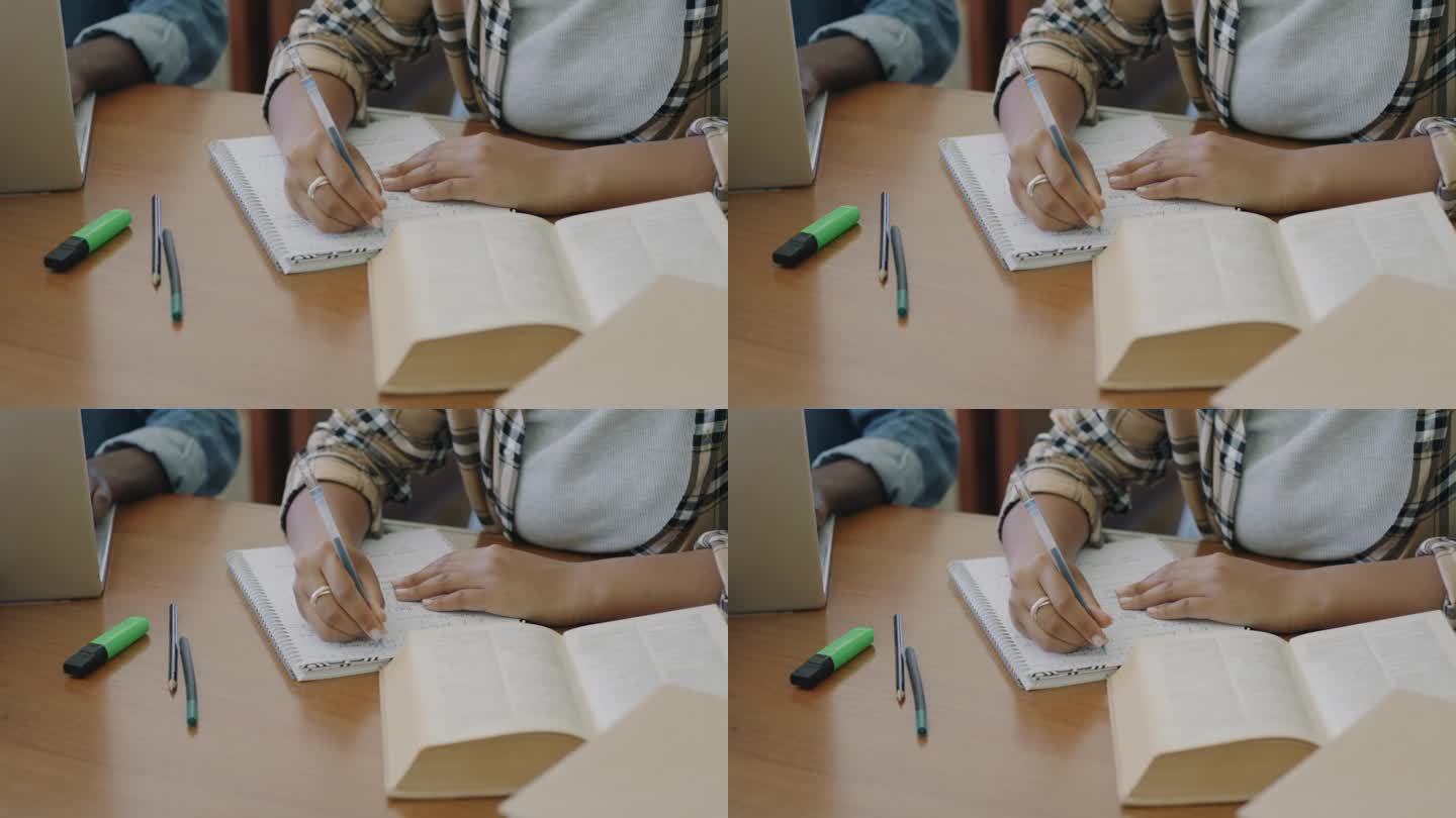 手的特写，学生在桌子上学习，用笔记本电脑打字，记笔记，看书