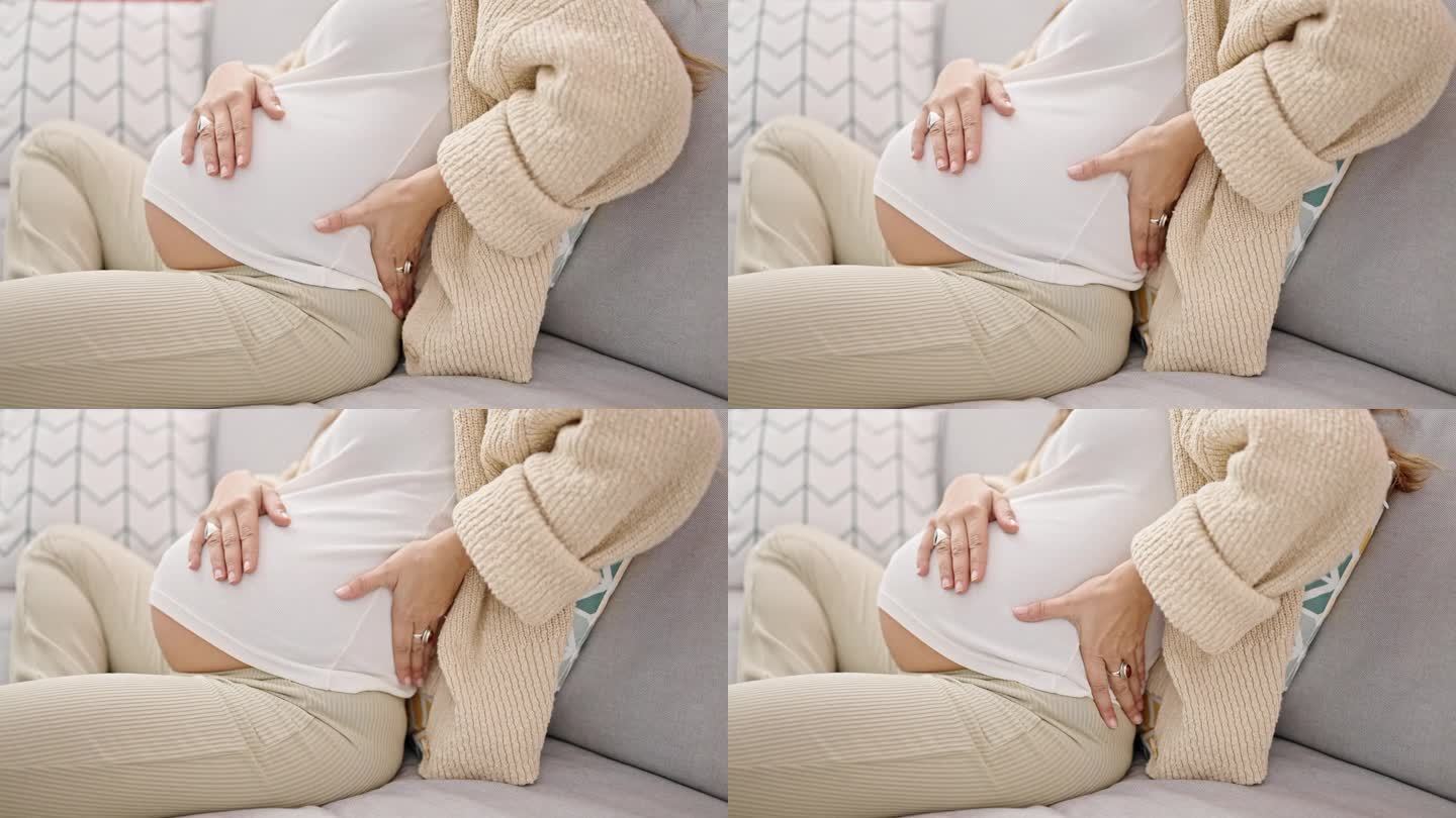 一位腰酸背痛的年轻孕妇坐在家里的沙发上