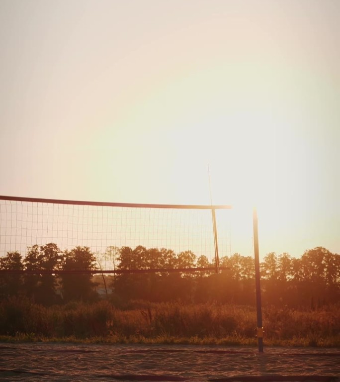 沙滩排球场与轮廓的网在日落。垂直视频