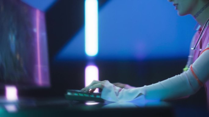 一个快乐的女孩在电脑上玩网络游戏的肖像。时尚的玩家在未来的霓虹灯工作室玩游戏。360度移动镜头与放大