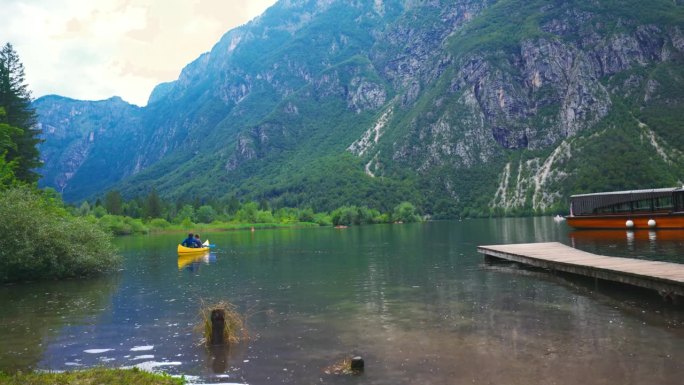 湖边田园诗般的夏日。游客在湖上划独木舟，背景是山脉