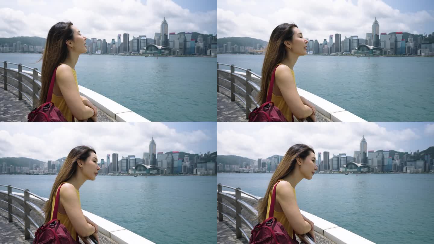 亚洲年轻女子在维多利亚港观光，眺望香港城市